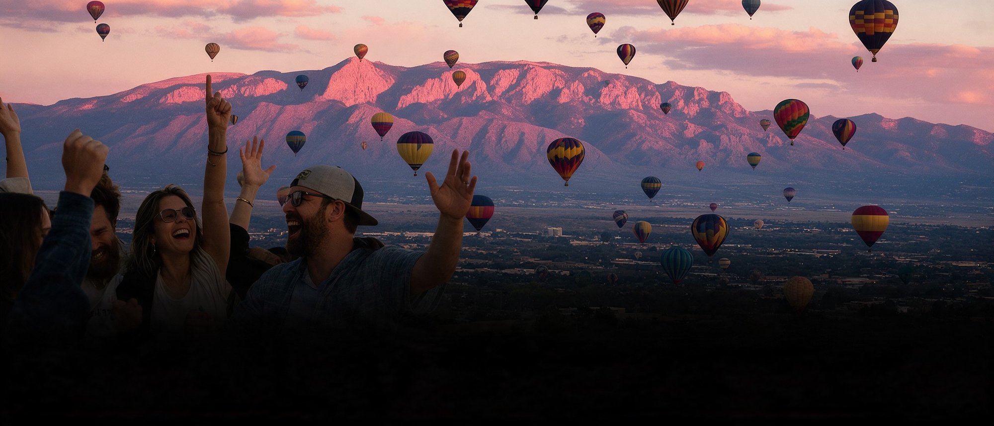 Hot air balloons over Albuquerque at sunset with friends cheering in the foreground
